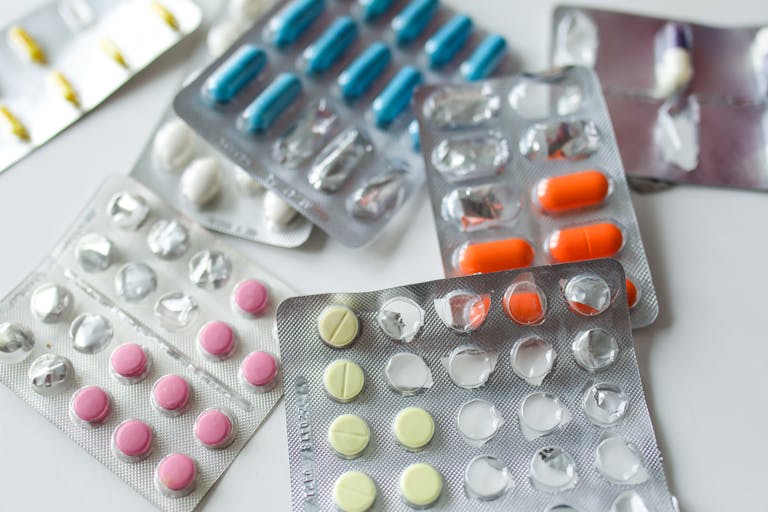 Assorted colorful blister packs of pills and capsules on a white surface.